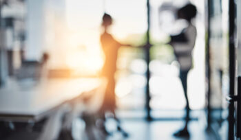 Verblasste Aufnahme von zwei Frauen, die Hände schütteln.