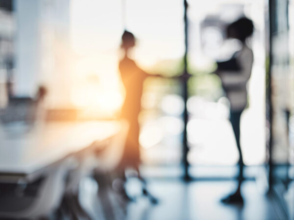 Verblasste Aufnahme von zwei Frauen, die Hände schütteln.